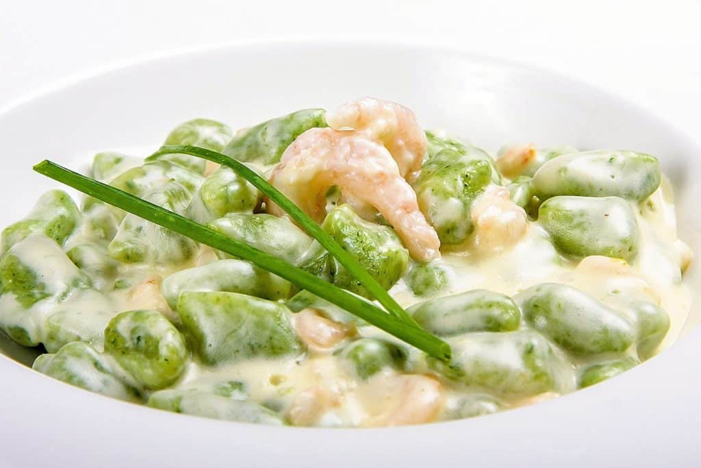 Spinach gnocchi with shrimps in cheese sauce
